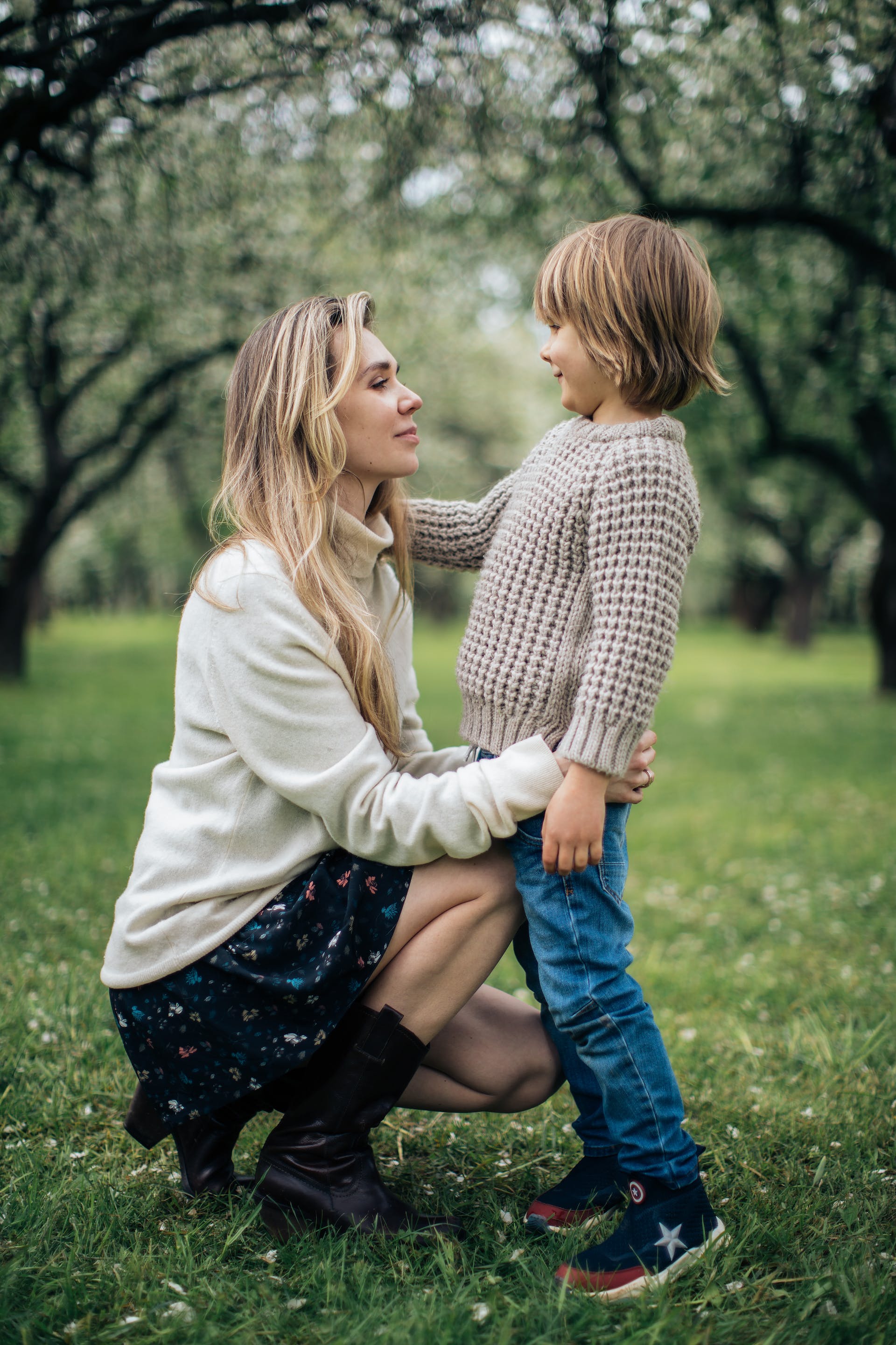 Une mère et son enfant debout sur un terrain herbeux tout en se regardant l'un l'autre | Source : Pexels